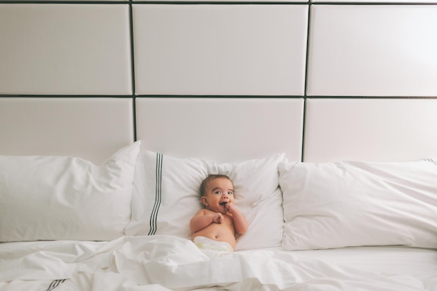 Portret van een baby jongen die thuis op bed ligt