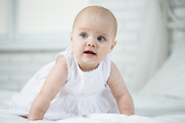 Portret van een baby op het bed in haar kamer