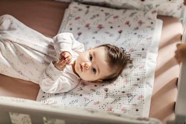 Portret van een babymeisje dat in haar wieg ligt en naar de camera kijkt