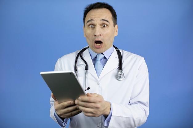 Portret van een bang volwassen mannelijke arts in witte medische jas met tablet