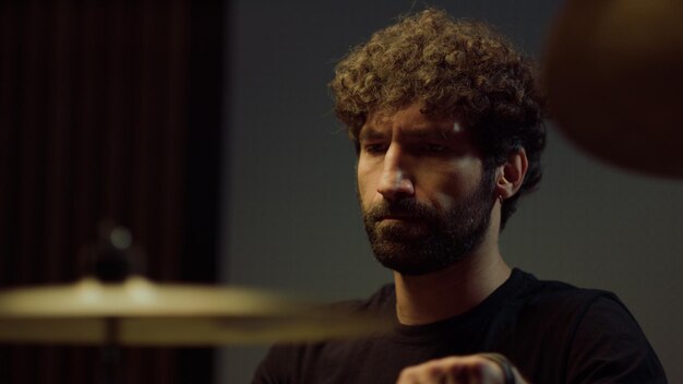 Portret van een bebaarde drummer die solo speelt op drumbekkens in de opnamestudio