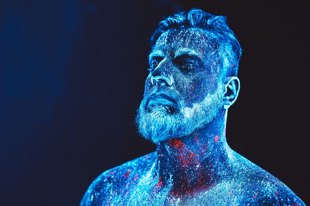 Portret van een bebaarde man. De mens is geschilderd in ultraviolet poeder.