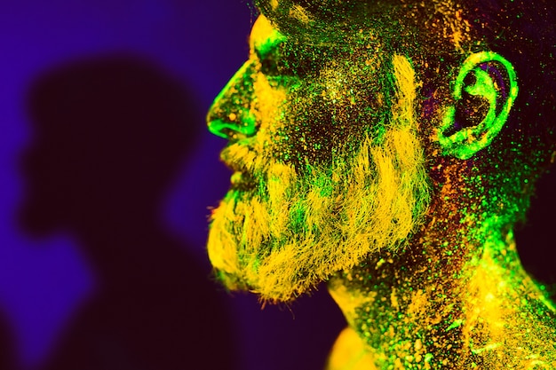 Portret van een bebaarde man. De mens is geschilderd in ultraviolet poeder.
