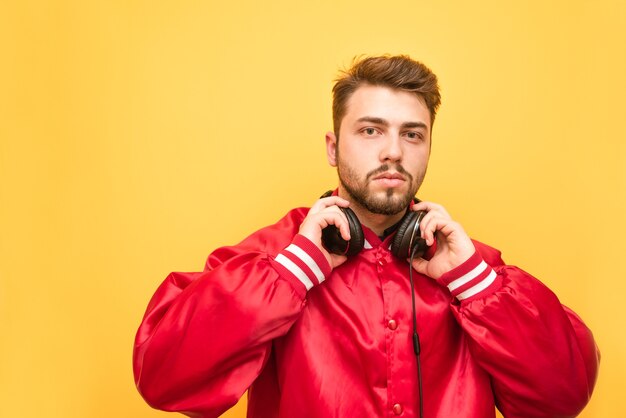 Portret van een bebaarde man in zijn koptelefoon en een rood jasje op geel