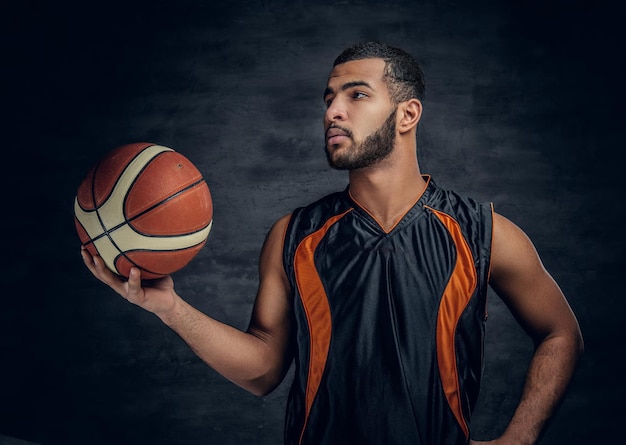 Portret van een bebaarde zwarte man houdt een basketbal vast.
