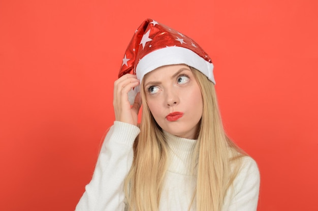 Foto portret van een bedachtzame jonge vrouw in een kerstmanhoed