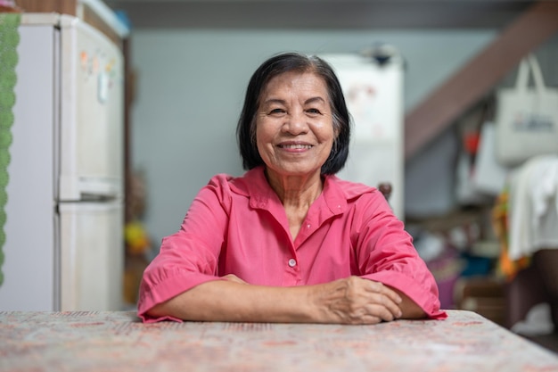 Portret van een bejaarde Aziatische vrouw die thuis glimlacht en naar de camera kijkt