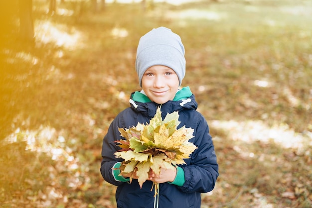 portret van een blanke gelukkige jongen met herfstbladeren, ruimte voor tekst, seizoen