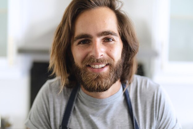 Foto portret van een blanke man in de keuken die naar de camera kijkt en glimlacht