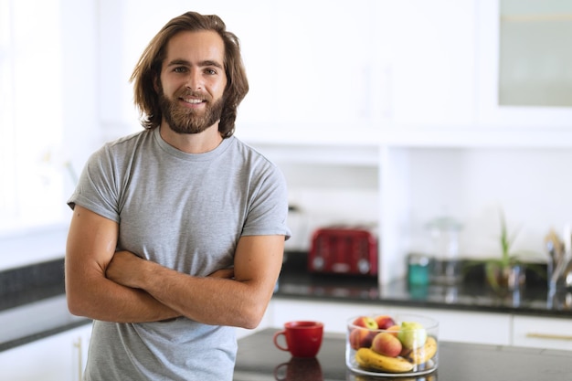 Portret van een blanke man in de keuken glimlachend met gekruiste armen