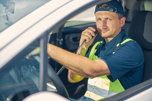 Portret van een blanke man met een portofoon die in een auto zit