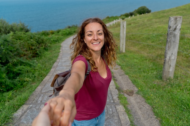 Portret van een blanke vrouw die de hand naar de camera reikt in een groen pad. Horizontale weergave van backpacker op avontuurlijke reis. Mensen en reisbestemmingsconcept.