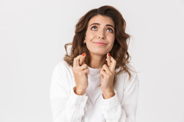 Portret van een blanke vrouw die in vrijetijdskleding vingers gekruist houdt terwijl hij staat, geïsoleerd over wit