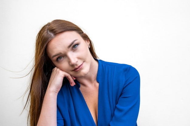 Portret van een blanke vrouw met lang rood haar en blauwe ogen, intens en diep kijkend naar de camera