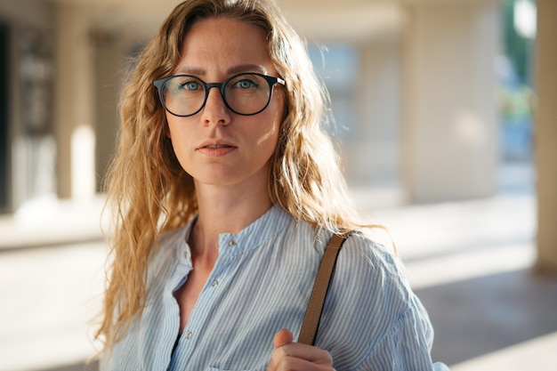 Portret van een blanke vrouwelijke zakenman in een bril op straat in de stad