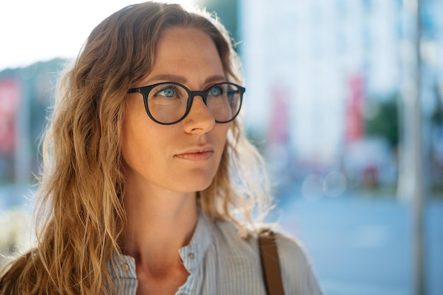 Portret van een blanke vrouwelijke zakenman in een bril op straat in de stad