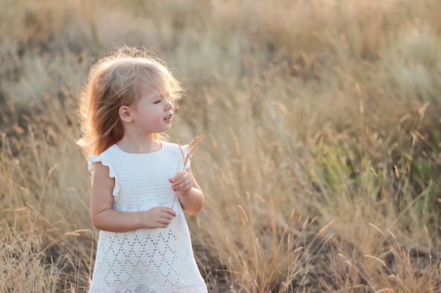 Portret van een blond meisje bij zonsondergang in de natuur