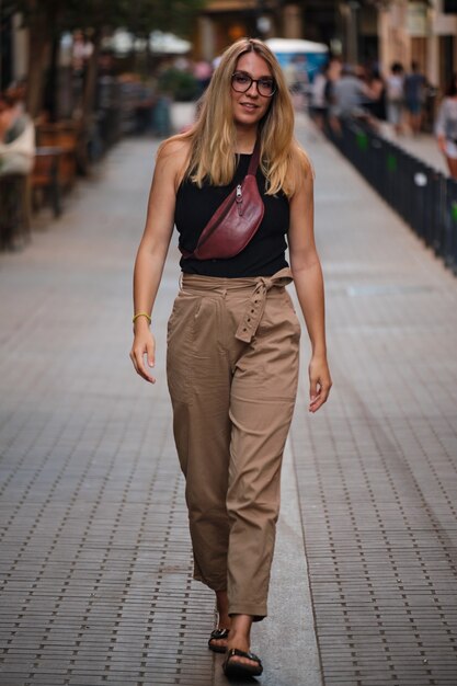 Portret van een blond meisje met een bril die poseert voor een fotoshoot op een straat in de stad barcelona.