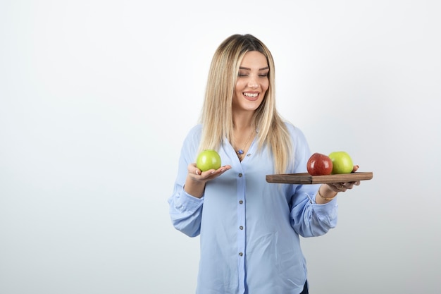 Portret van een blond meisje met houten bord met groene en rode appels