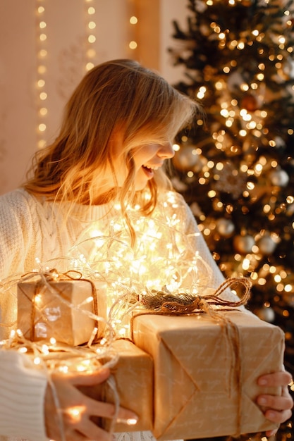 Portret van een blonde vrouw die bij de kerstboom zit