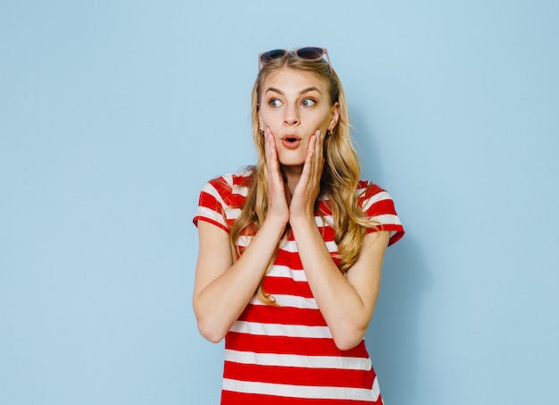 Portret van een blonde vrouw die gekleed is in een rode trui en glimlacht in de kamer en gebaren