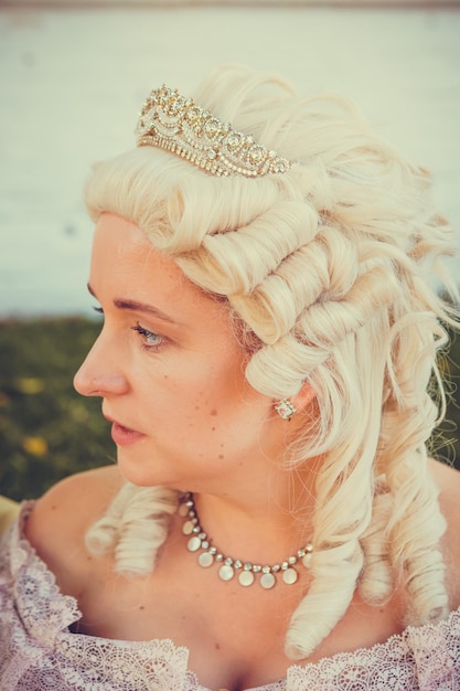 Portret van een blonde vrouw gekleed in historische barokke kleding met een ouderwets kapsel