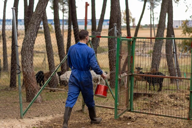 Portret van een boer met een emmer voedsel om de dieren op zijn boerderij te voeren