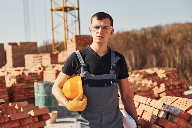 Portret van een bouwvakker in uniform en veiligheidsuitrusting die op het dak van een onafgewerkt gebouw staat