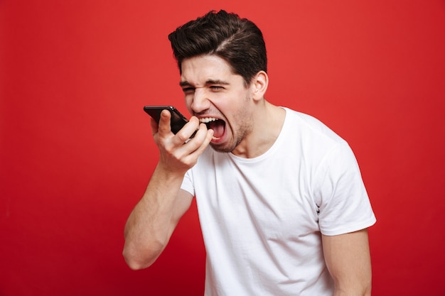 Portret van een boze jonge man in wit t-shirt schreeuwen