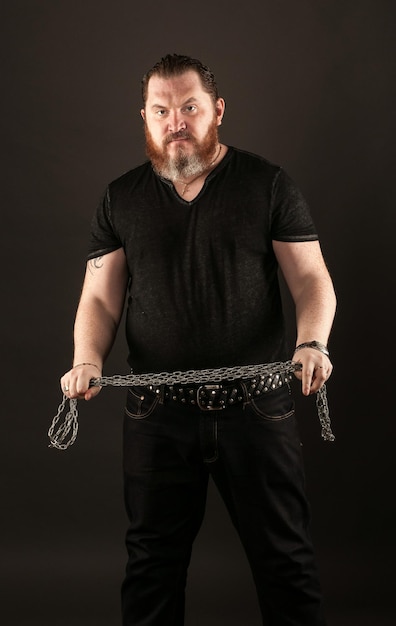 Foto portret van een boze man met ketting tegen een zwarte achtergrond