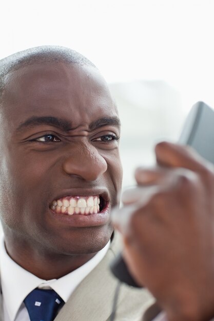 Portret van een boze zakenman die zijn telefoonzaktelefoon bekijkt