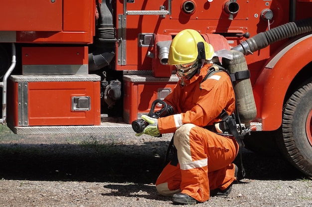 Portret van een brandweerman die een brandbestrijdingspak draagt met een achtergrond voor een watertruck met apparatuur