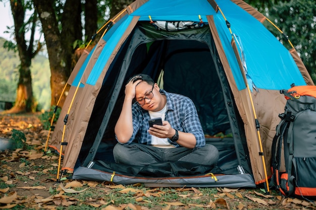 Portret van een bril van een Aziatische reiziger die smartphone gebruikt in tentenkamperen Buiten reizend kamperen en levensstijlconcept