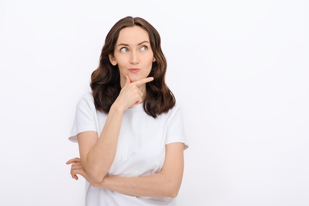 Portret van een brunette blanke vrouw met een bedachtzaam gezicht die wegkijkt in het witte T-shirt op een witte achtergrond kopie ruimte sjabloon