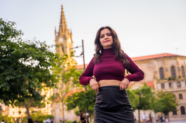 Portret van een brunette Latijns-vrouw met een leren rok naast een kerk die de levensstijl van de stad bezoekt