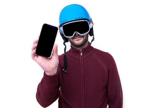 Portret van een brutale man in een skihelm en bril met een mobiele telefoon