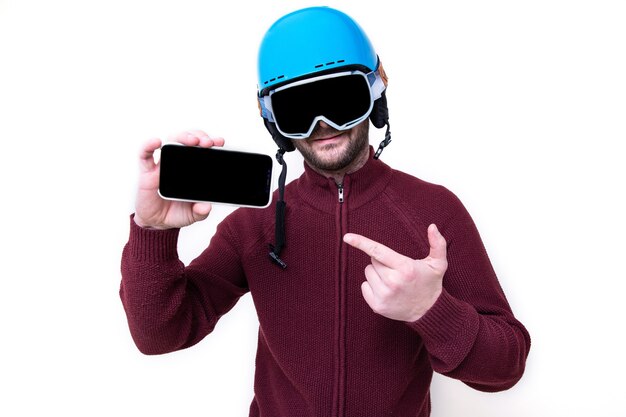 Portret van een brutale man in een skihelm en bril met een mobiele telefoon