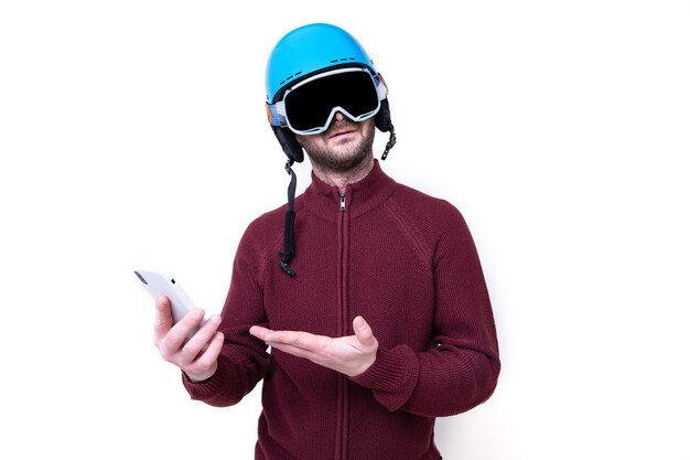 Portret van een brutale man in een skihelm en bril met een mobiele telefoon