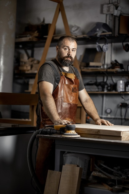 Portret van een brutale meestertimmerman in een schort in werkplaats