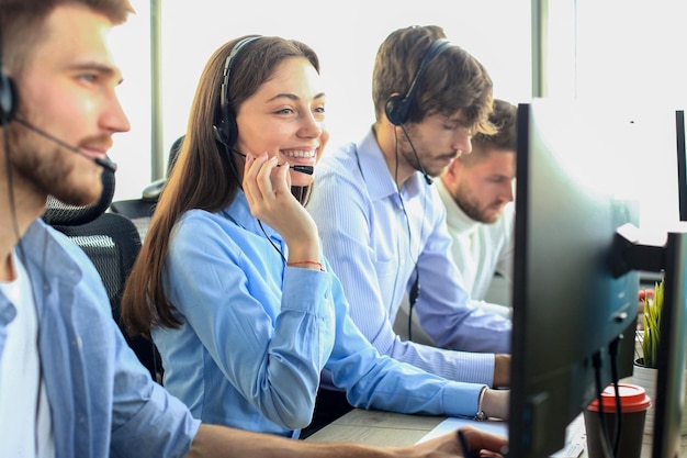 Portret van een callcentermedewerker vergezeld door haar team Glimlachende medewerker van de klantenservice op het werk