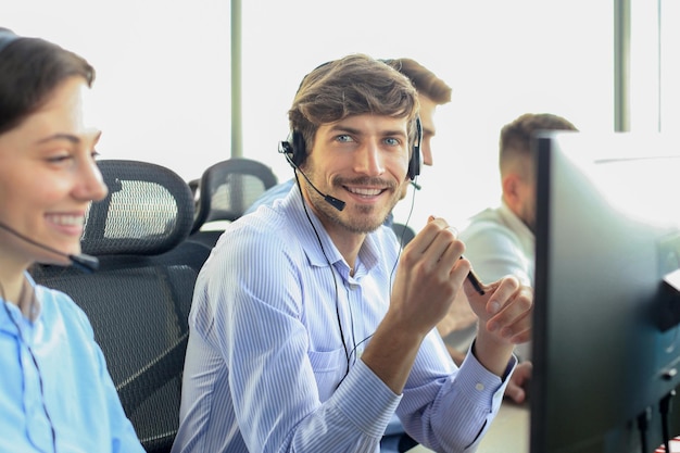 Portret van een callcentermedewerker vergezeld door zijn team Glimlachende medewerker van de klantenservice op het werk