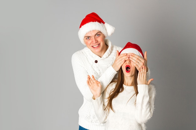 Portret van een charmant jong stel viert kerstmis in de studio op een grijze achtergrond