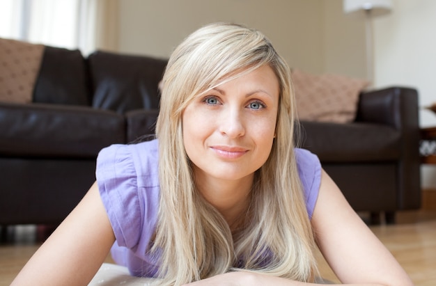 Portret van een charmante blonde vrouw op de vloer liggen