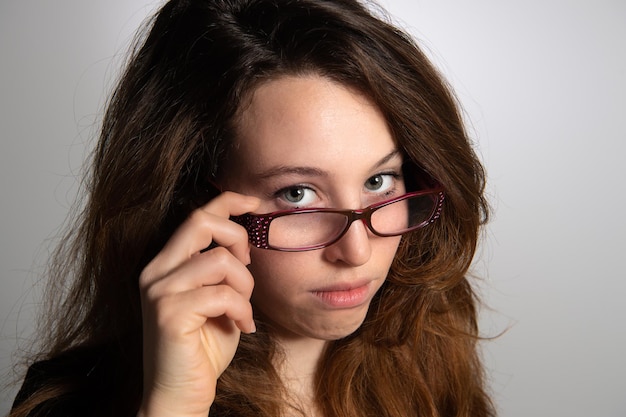 Portret van een charmante brunette vrouw die haar bril in de hand houdt geïsoleerd op een grijze achtergrondxDxA