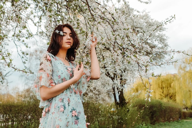 Portret van een charmante vrouw die zich voordeed in de buurt van appel-kersenboom bloeit bloeiende bloemen in de tuin