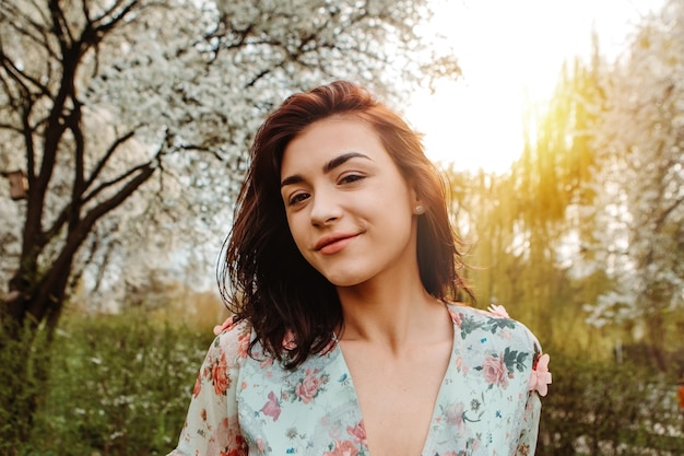 Portret van een charmante vrouw die zich voordeed in de buurt van appel-kersenboom bloeit bloeiende bloemen in de tuin