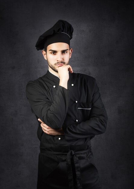 Portret van een chef-kok fornuis in zwarte uniform grijze achtergrond