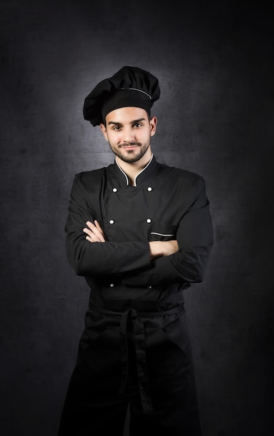 Portret van een chef-kok fornuis in zwarte uniform grijze achtergrond