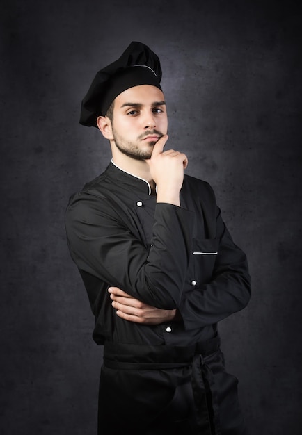 Portret van een chef-kok fornuis in zwarte uniform grijze achtergrond