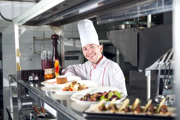 Portret van een chef-kok met gekookt voedsel in de keuken in het restaurant.